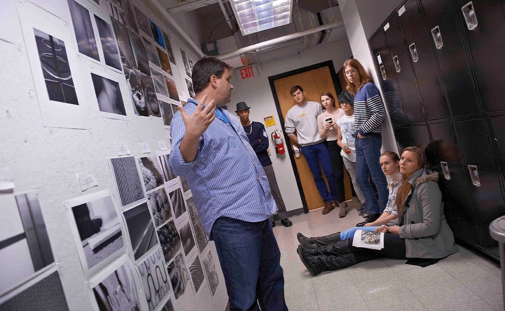 Students listen to professor critique their photography assignments